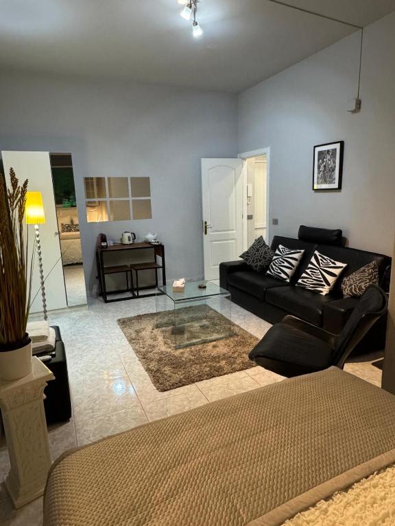 a living room with a black couch and a glass table at Basement Apartment Studio in San Bartolomé