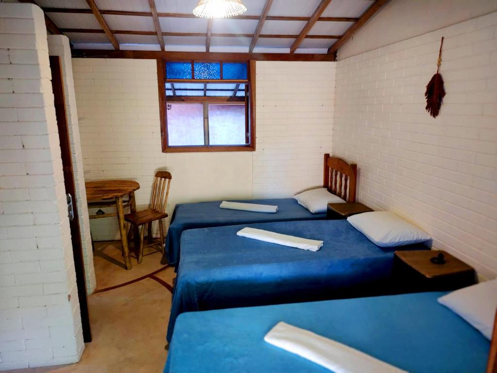 - 2 lits dans une chambre avec des draps bleus et une table dans l'établissement Cumbuca Hostel, à Porto Seguro