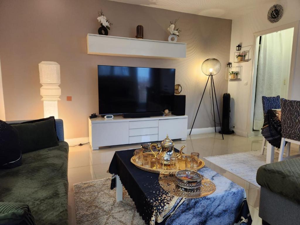 un salon avec une grande télévision et une table dans l'établissement L'orient de Paris, à Créteil