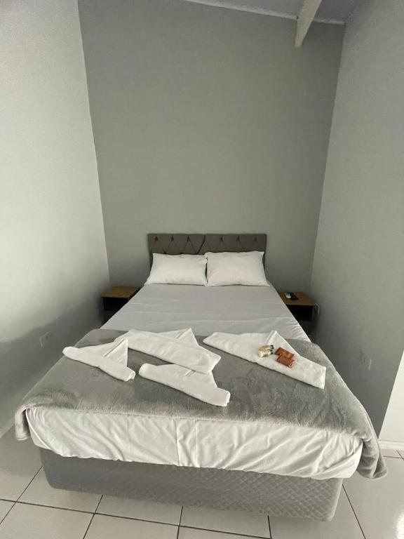 a bed with white sheets and towels on it at Pousada e casa Villa Siri in Ubatuba