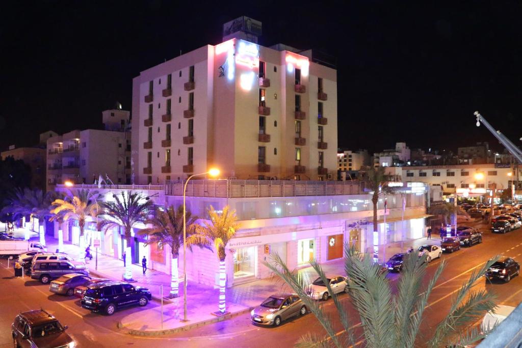 un gran edificio con coches estacionados en un estacionamiento en Al Raad Hotel, en Áqaba