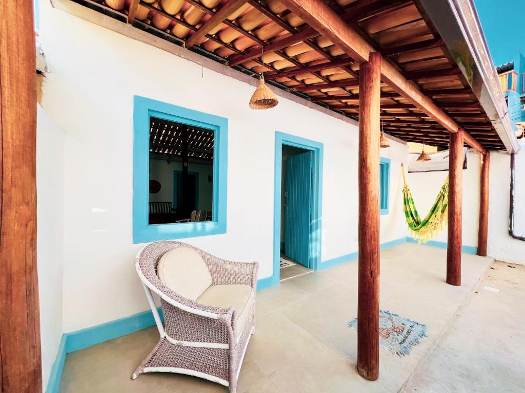 a patio with a wicker chair under a pergola at Casa da Dona Filhinha, paz e localização perfeita na vila da Praia do Forte BA in Mata de Sao Joao