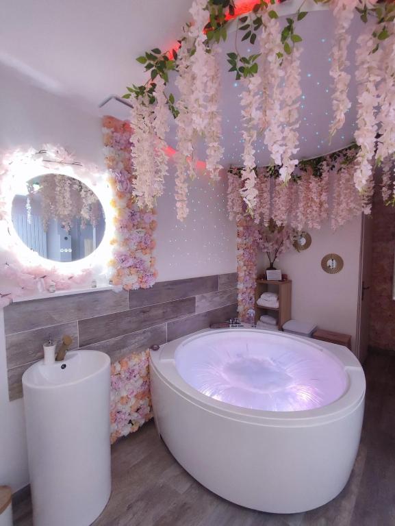 La salle de bains est pourvue d'une baignoire et de fleurs. dans l'établissement Cocon des Merveilles - balnéo ronde avec cascade, au Havre