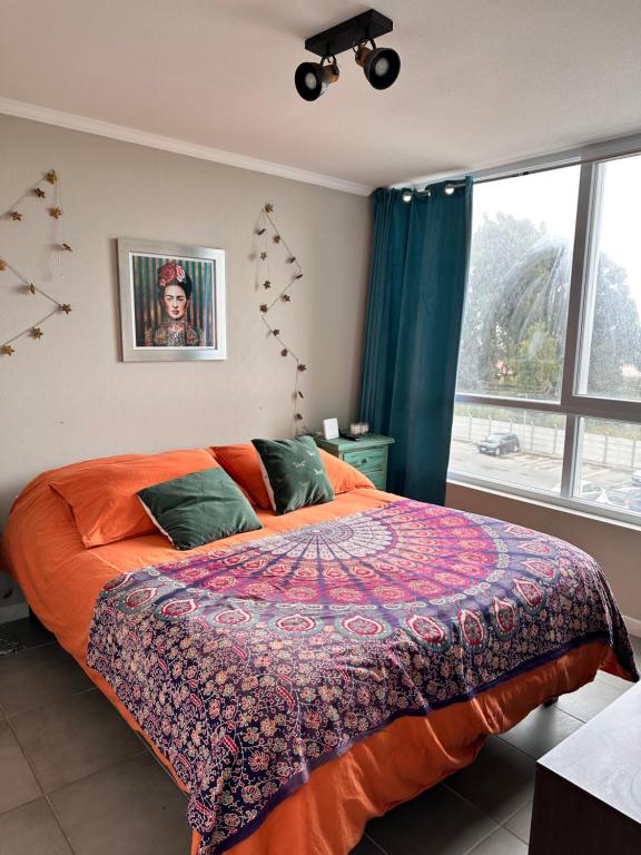 a bedroom with a bed with an orange blanket and a window at la serena 1 dormitorio in La Serena