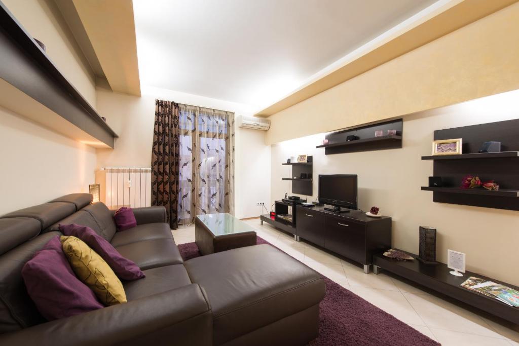 a living room with a leather couch and a tv at City Apartments in Sofia