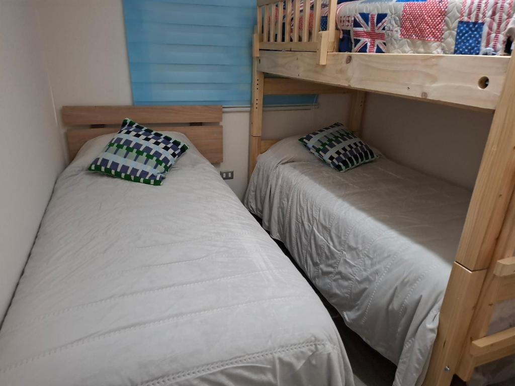 2 bedden in een kamer met een stapelbed bij GiGIi in La Serena
