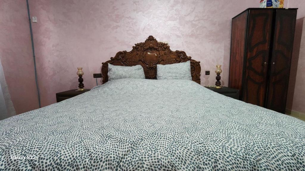 a bedroom with a large bed with a wooden headboard at Appartement B à 7min de l’aéroport de Marrakech in Marrakech