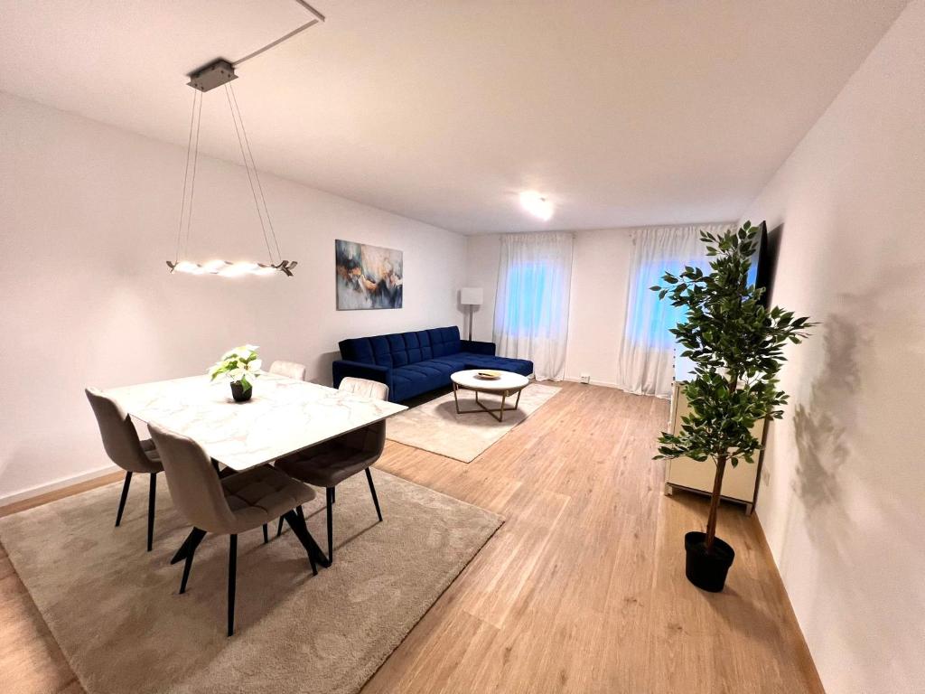 a living room with a table and a blue couch at Designer Apartment in Sinsheim Erstbezug 75 TV mit Netflix und offene Küche WeHome Premium in Sinsheim
