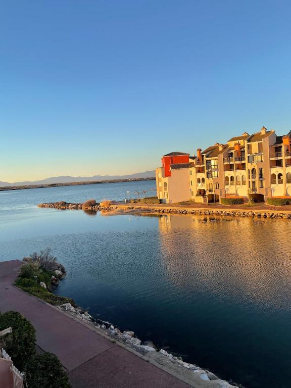un groupe de bâtiments à côté d'une masse d'eau dans l'établissement Superbe appartement moderne avec piscine, au Barcarès