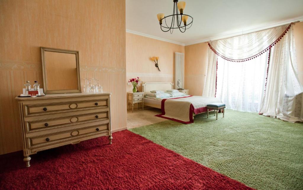 a bedroom with a bed and a dresser with a mirror at Hotel Pałacyk Konin in Konin