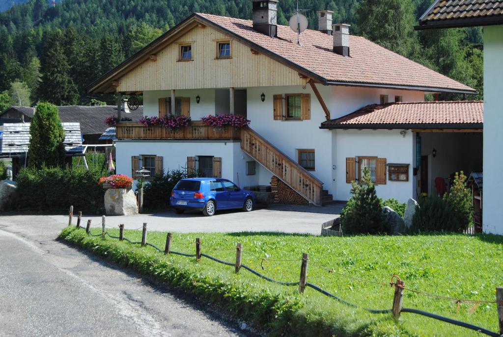 a house with a blue car parked in front of it at Trogerhof in Dobbiaco