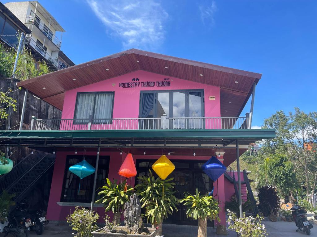 ein rosafarbenes Haus mit bunten Lichtern davor in der Unterkunft Thương Thương Đà Lạt 2 in Xuan An