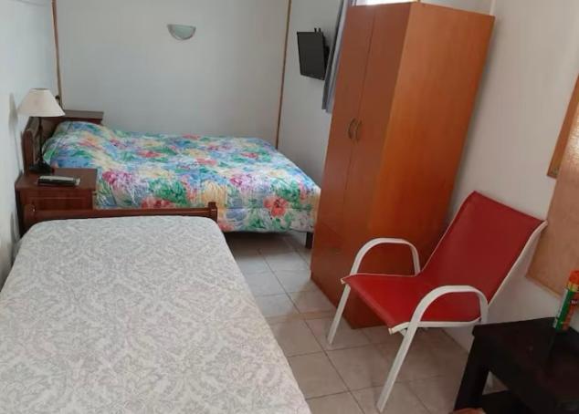 a small bedroom with a bed and a red chair at Cabaña Venti in Bahia Inglesa