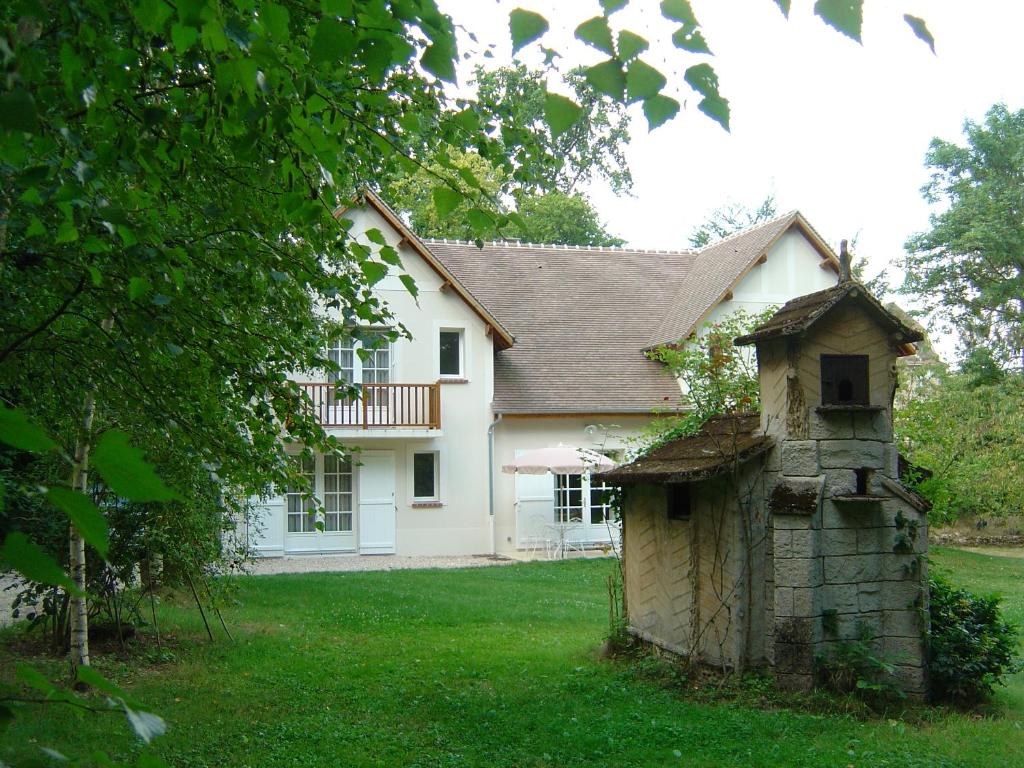una casa blanca con una casa de pájaros en el patio en Domaine De Chantemerles en Fontainebleau
