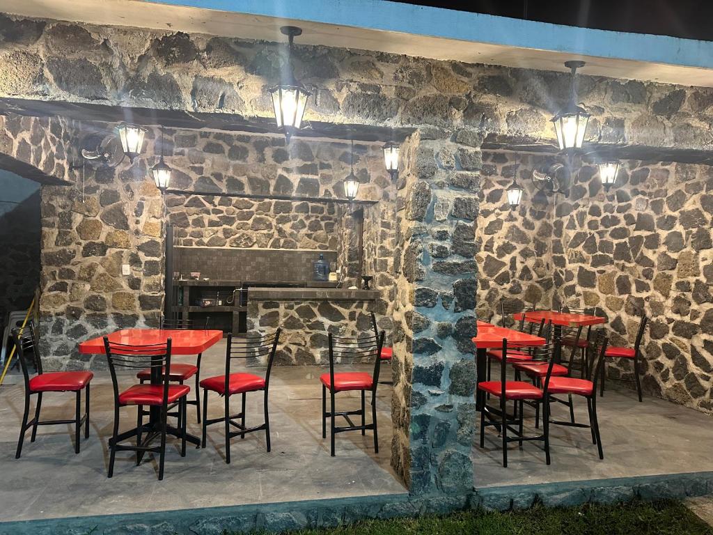 un ristorante con tavoli e sedie rossi di fronte a un muro di pietra di Rancho MM a Temixco