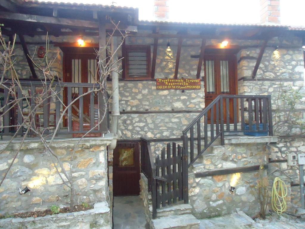 a stone building with a staircase and a sign on it at Traditional Guesthouse Archontoula in Palaios Panteleimonas