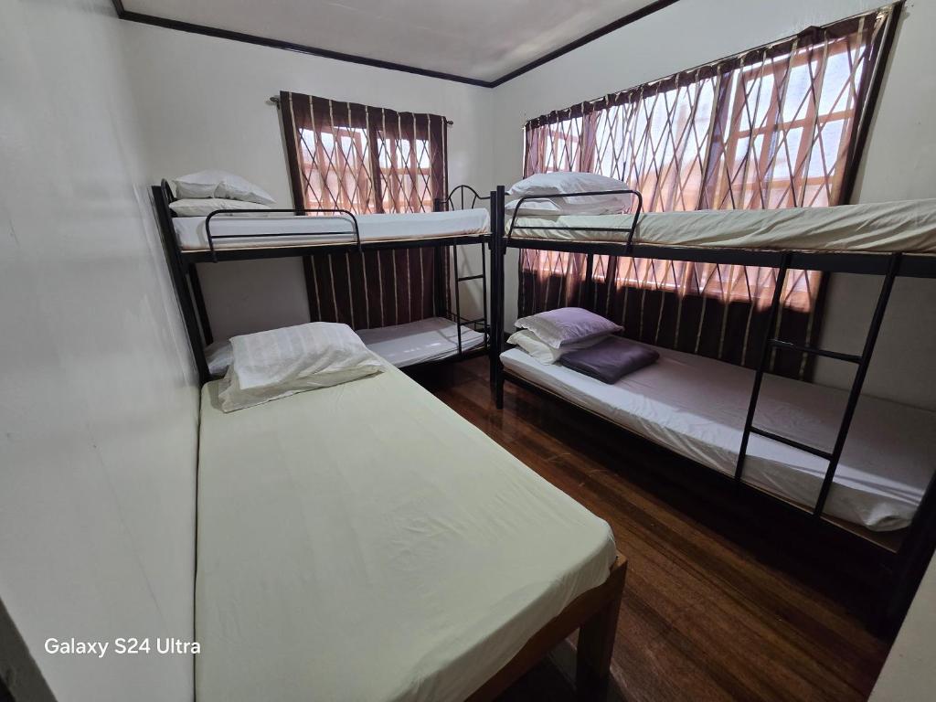 バギオにあるHillside Vacationers homestayの二段ベッドが2つと窓が2つある部屋
