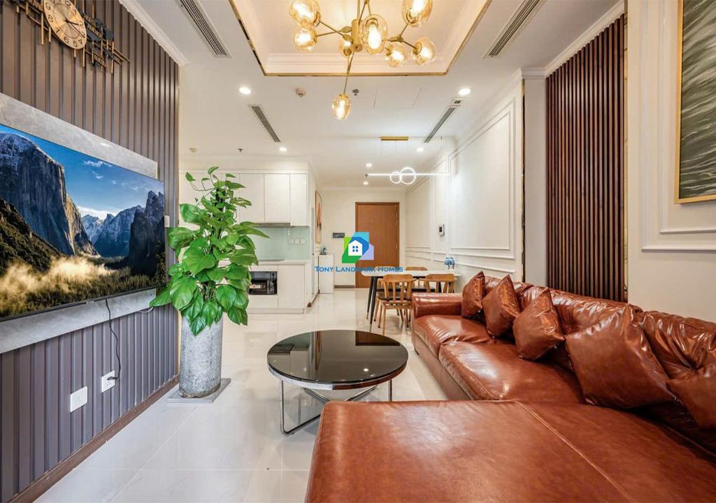 a living room with a brown leather couch and a table at the Vinhome Central apartment - The Best Landmark Area in Ho Chi Minh City