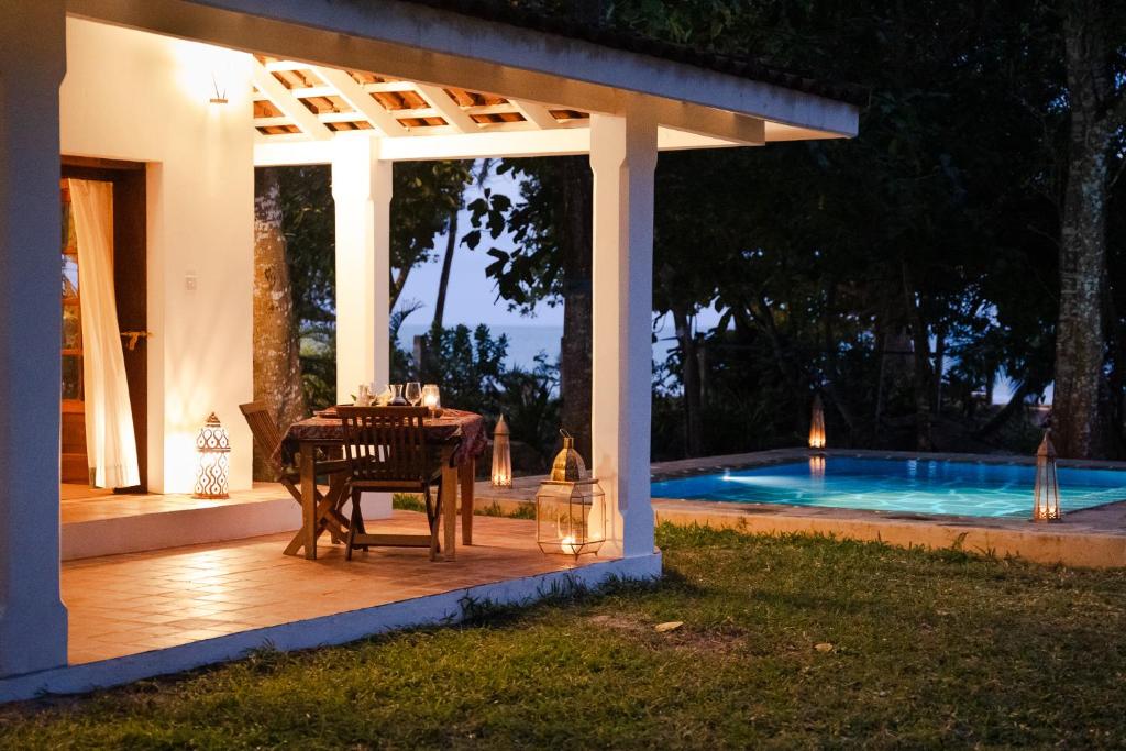 a table under a pergola next to a swimming pool at Mawimbi Cottage in Ukunda