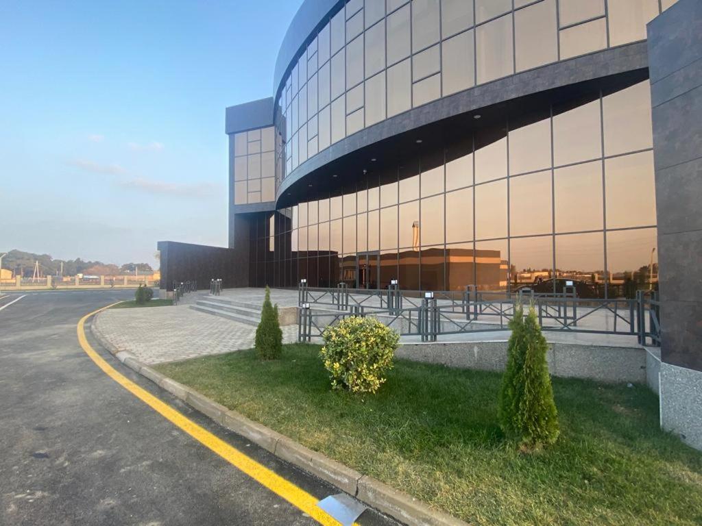 a large glass building with a parking lot in front of it at Arena Hotel Neftchala in Neftçala