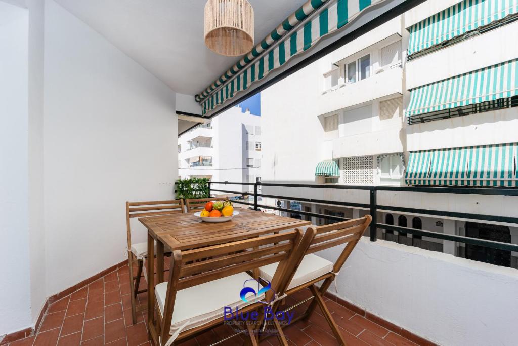Un balcón con una mesa de madera y un bol de fruta. en At The Plaza Central Beach Flat, en La Herradura
