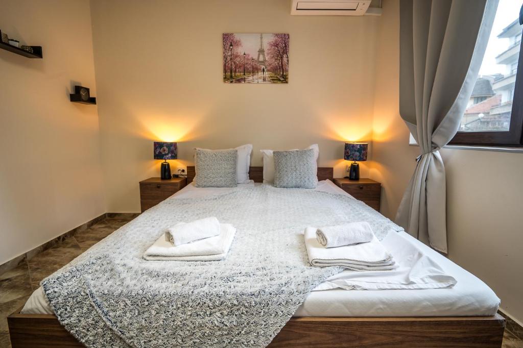 a bedroom with a large white bed with two lamps at Къща за гости Алекс in Karlovo