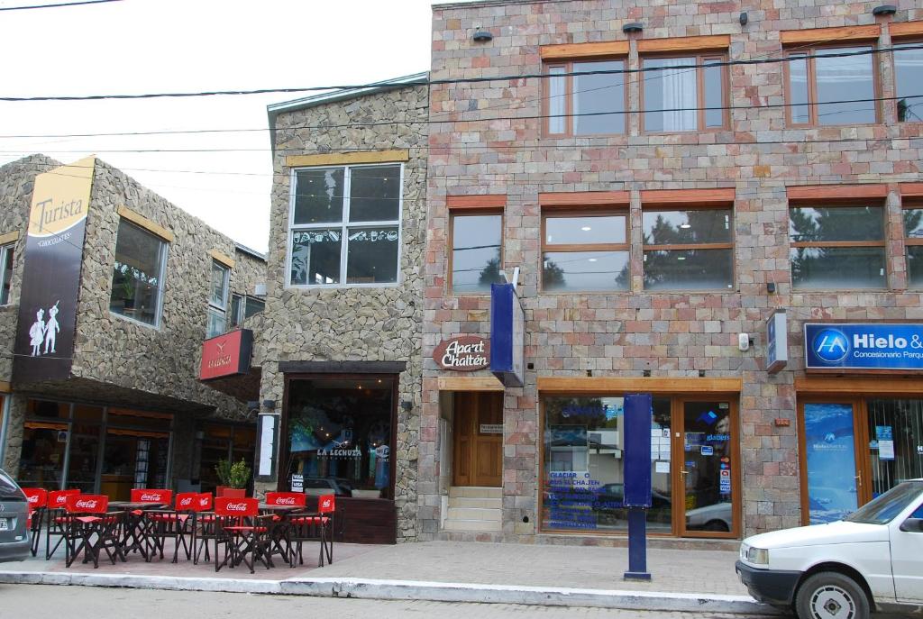 un edificio de ladrillo con mesas rojas y sillas en una calle en Apart Chalten en El Calafate