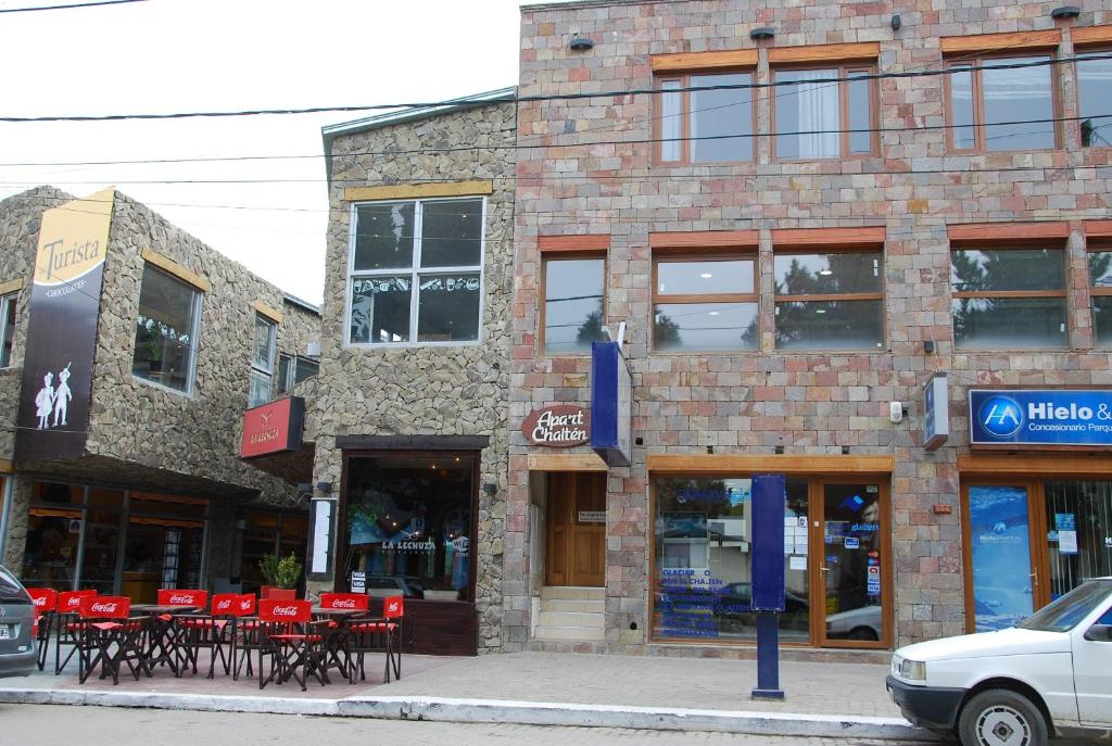 a brick building with red tables and chairs on a street at Apart Chalten in El Calafate