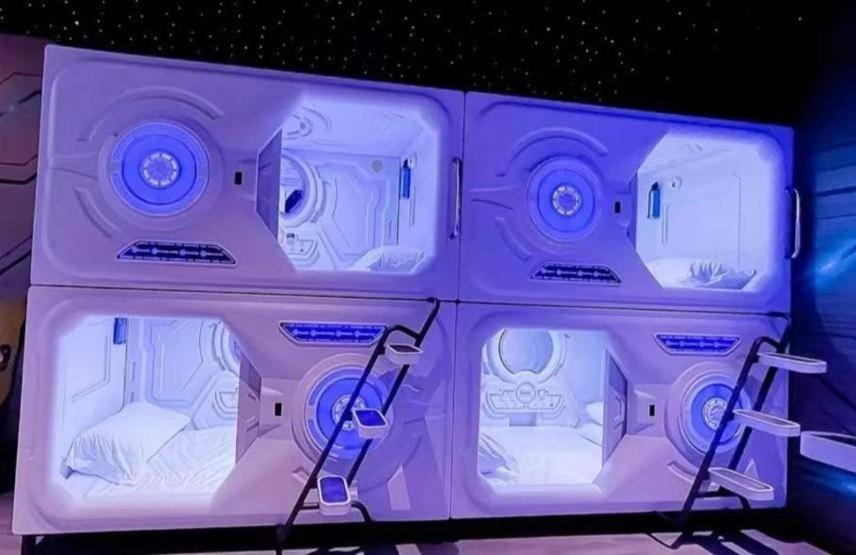 a room with four beds in it with purple lighting at bambu hostel capsules in Seville