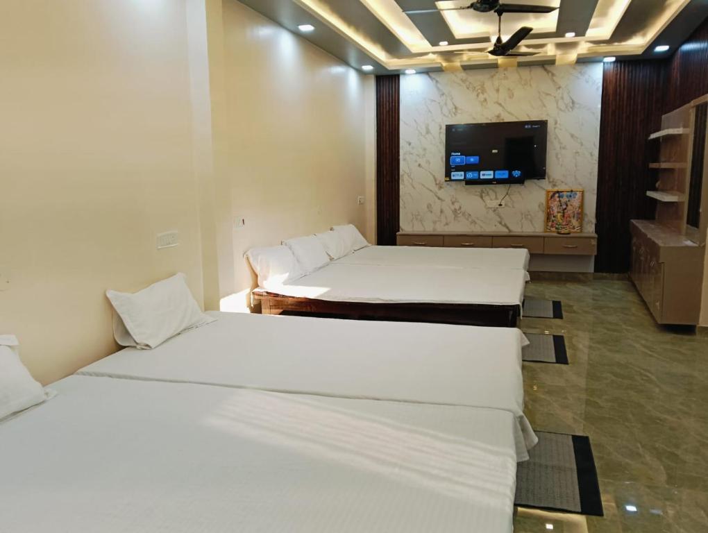 a room with three beds and a tv on the wall at Shri SeetaRam Home Stay Near Shri Ram Janmabhoomi Mandir Ayodhya in Ayodhya