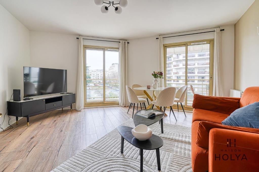 un salon avec un canapé, une télévision et une table dans l'établissement Le Grandiose - Aux portes de Paris - 328B, à Levallois-Perret