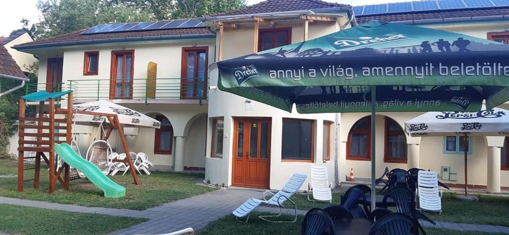 dom z placem zabaw z krzesłami i parasolem w obiekcie Aqua Hostel w Siófoku