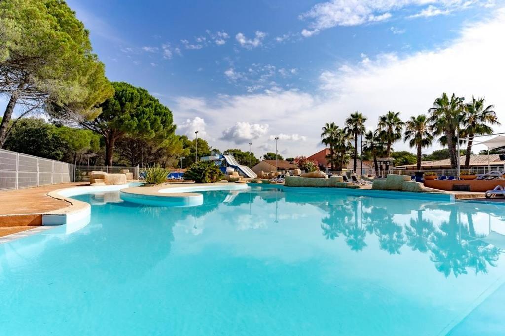 une grande piscine avec de l'eau bleue dans l'établissement MOBIL-HOME, 6 pers, 3 ch, 2 sdb, oasis village 5 ÉTOILES, à Puget-sur Argens