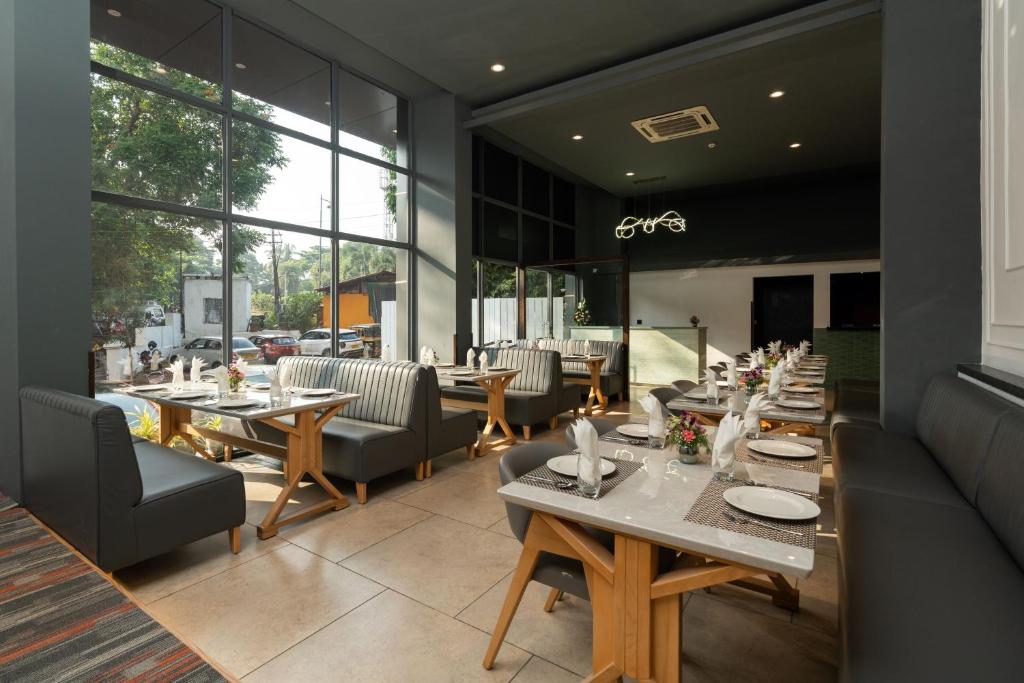 a restaurant with tables and chairs and windows at The Grand Central in Dona Paula