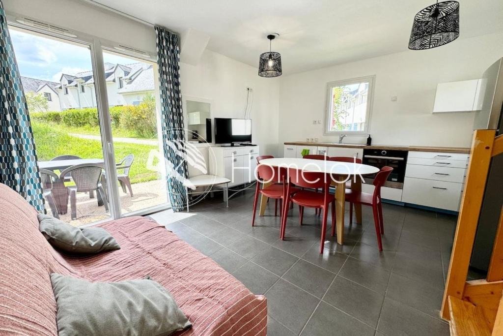 a kitchen and living room with a table and chairs at Maisonnette tout confort - Golf - Piscine in Quéven