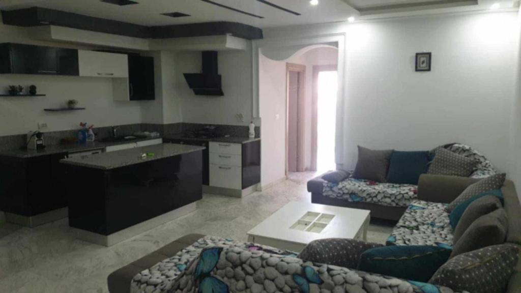 Una sala de estar con un sofá y una cocina. en Résidence la sirène Soviva, en Sousse