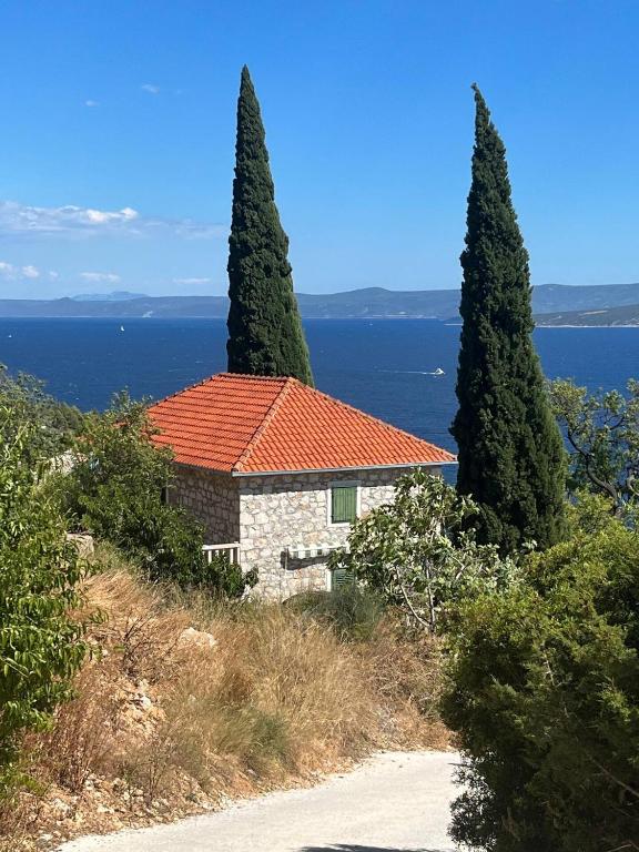 a house with an orange roof and two trees at Kameni cvijet in Murvica