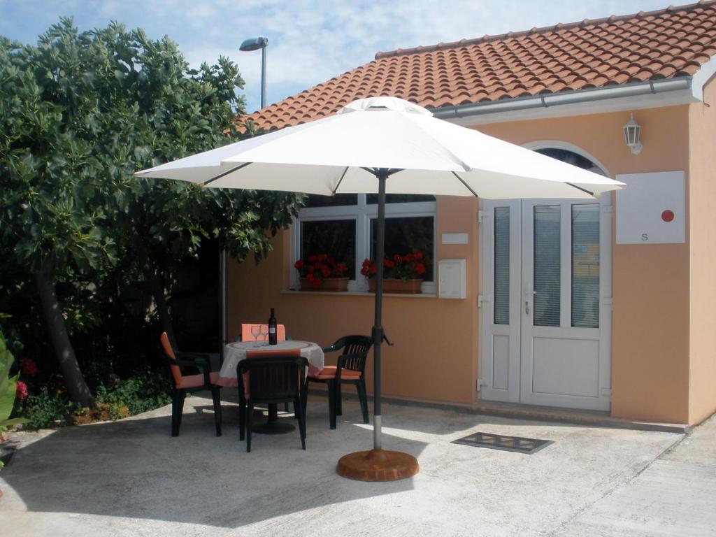 a table with a white umbrella in front of a house at Apartment Gogi in Vodice