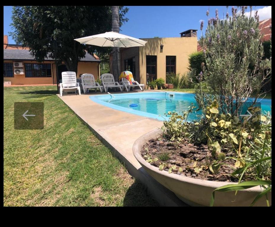 a swimming pool with an umbrella in a yard at QUINTA LA ARAUCARIA -Paraná in Paraná