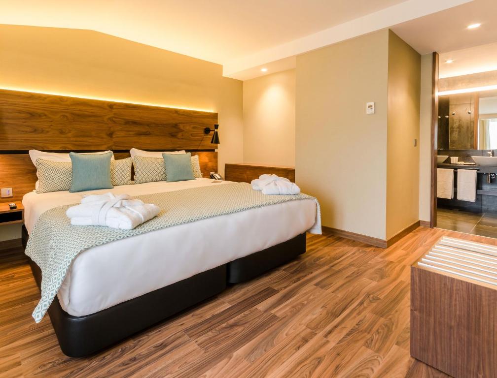 A warm-toned hotel bedroom with a large bed and adjoining bathroom.