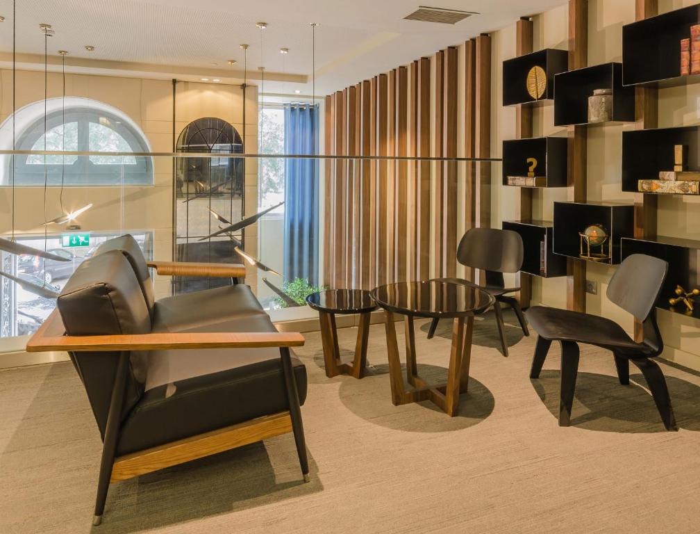 A stylish lounge with armchairs, small tables, and decorative shelving.