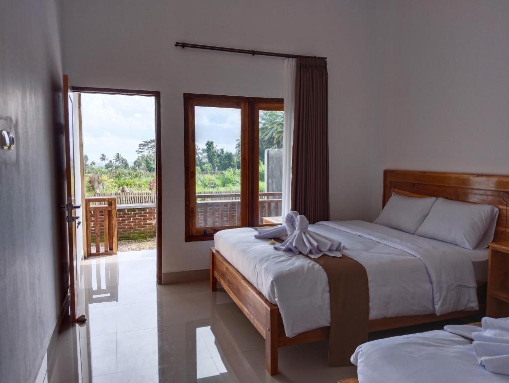 a bedroom with two beds and a balcony at Nan Bungalows Tetebatu in Tetebatu