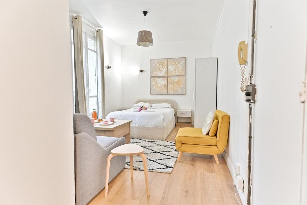 - une chambre blanche avec un lit et une chaise jaune dans l'établissement Peaceful Studio Parc des Buttes-Chaumont - II, à Paris