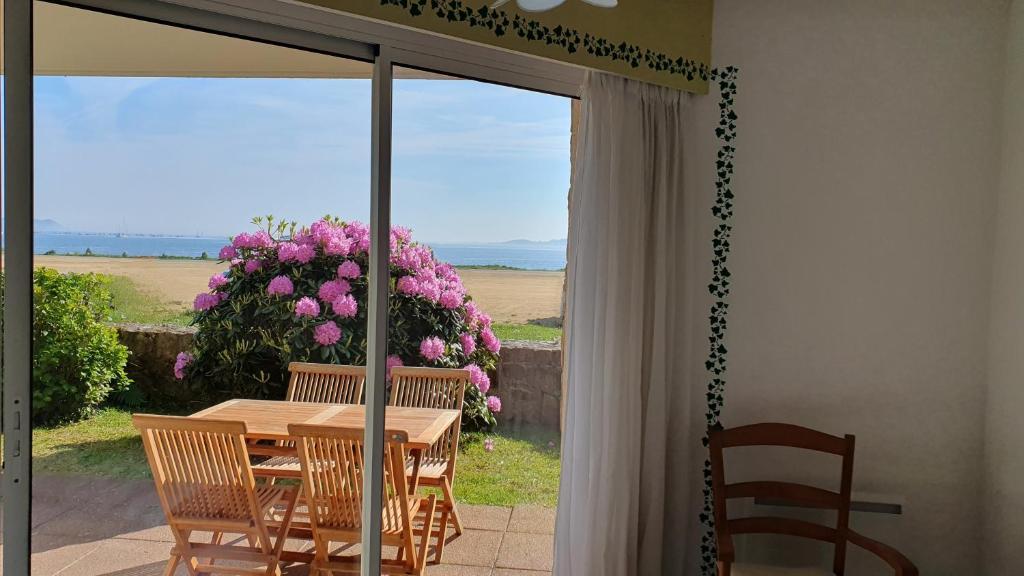 a table and chairs on a patio with a window at Appartement T2, RDJ, 2 étoiles, Vue mer panoramique, Côte de Granit Rose in Perros-Guirec