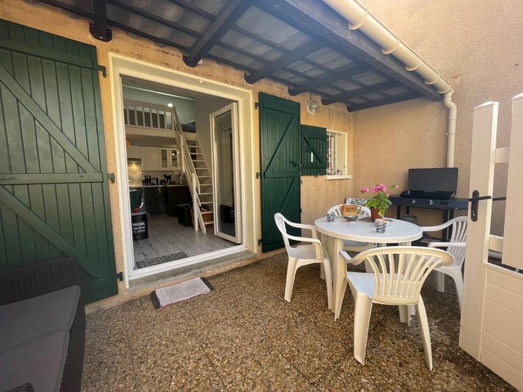 d'une terrasse avec une table, des chaises et une porte verte. dans l'établissement Maison 2 pièces mezzanine 4 couchages ST CYPRIEN PLAGE SC180-082, à Saint Cyprien Plage