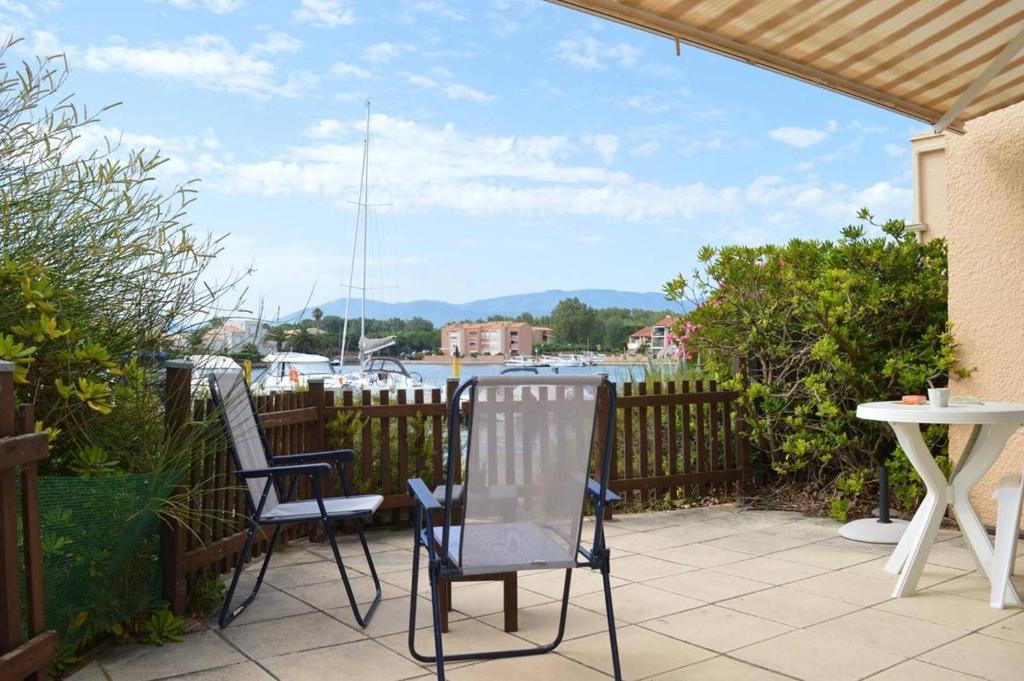 2 chaises et une table sur une terrasse avec un port de plaisance dans l'établissement Appartement Studio cabine 4 couchages SAINT CYPRIEN SC070-065, à Saint Cyprien Plage