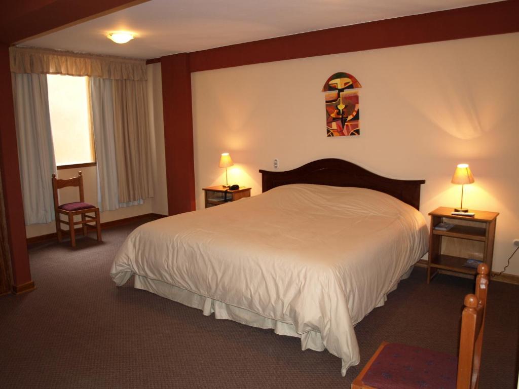 a bedroom with a bed and two tables and two lamps at Qelqatani Hotel in Puno