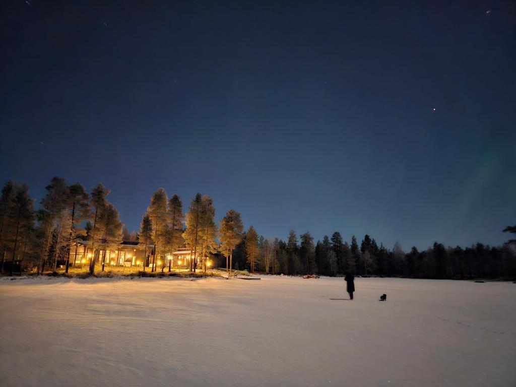 een persoon die 's nachts in een met sneeuw bedekt veld staat bij Villa Vilmala in Sääskilahti