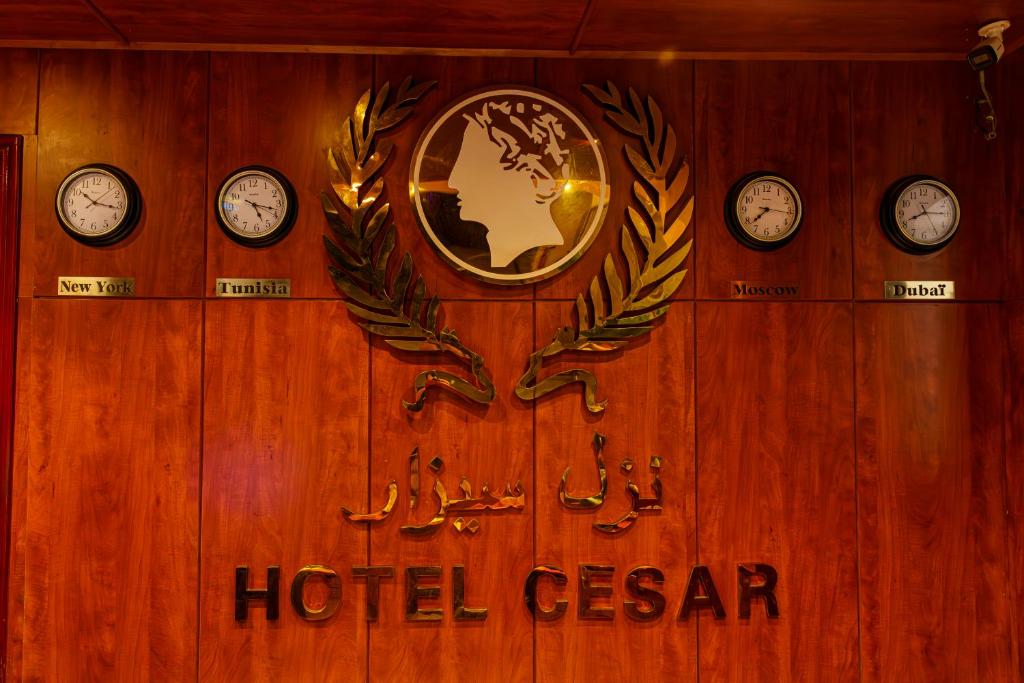 een houten wand met klokken en een hotelbord bij Cesar Palace Sousse in Sousse