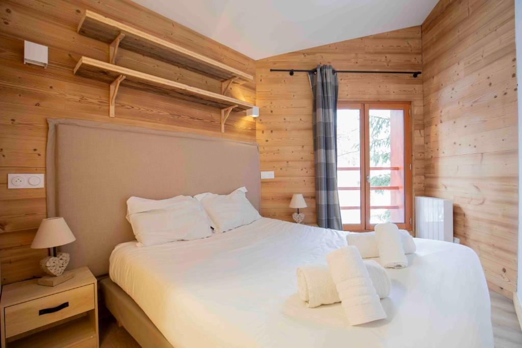 - une chambre avec un grand lit blanc et des murs en bois dans l'établissement Chalet Lougarou - Plagne 1800 - 8 personnes - ski au pied, à La Plagne Tarentaise